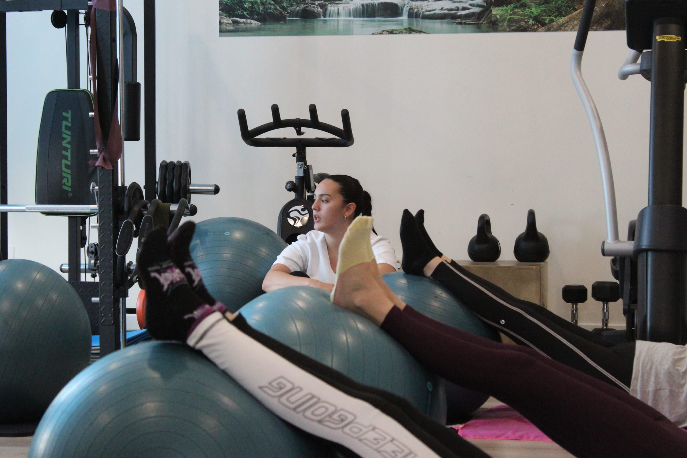 Clase de pilates en Ofisio: la profesional guía el ejercicio detrás de los fitballs mientras las alumnas apoyan las piernas en las pelotas